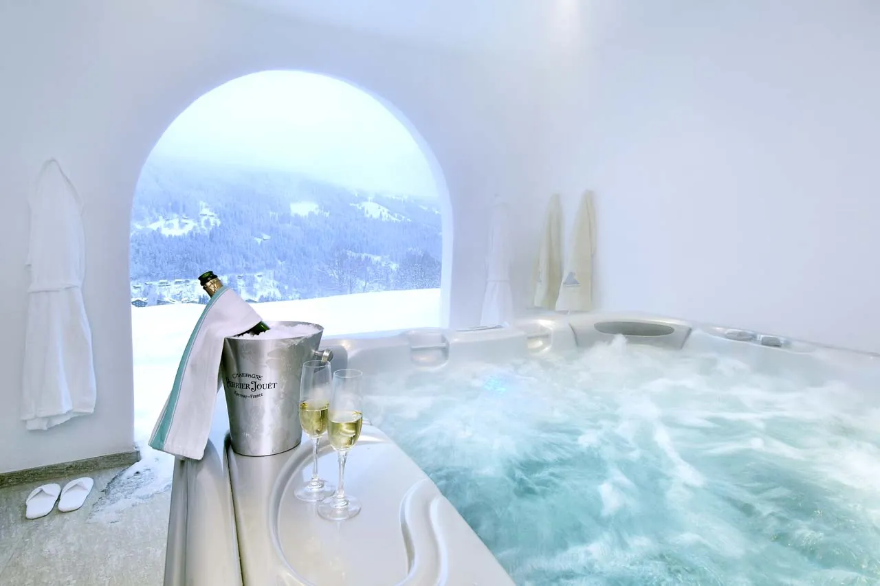 An outdoor hot tub under an arched opening with a snowy mountain view, Chalet Kolin, Klosters
