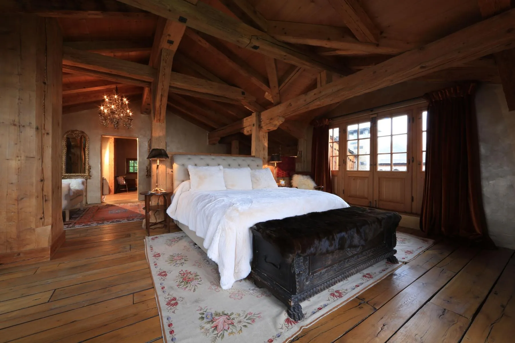 A bedroom under exposed timber beams at Chalet Kalem, Klosters