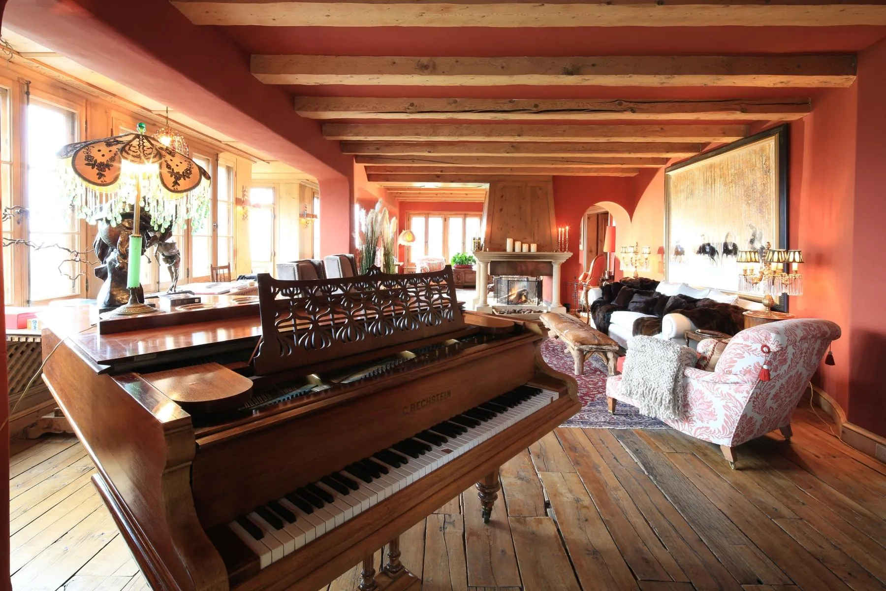 The drawing room at Chalet Kalem with a grand piano and red walls